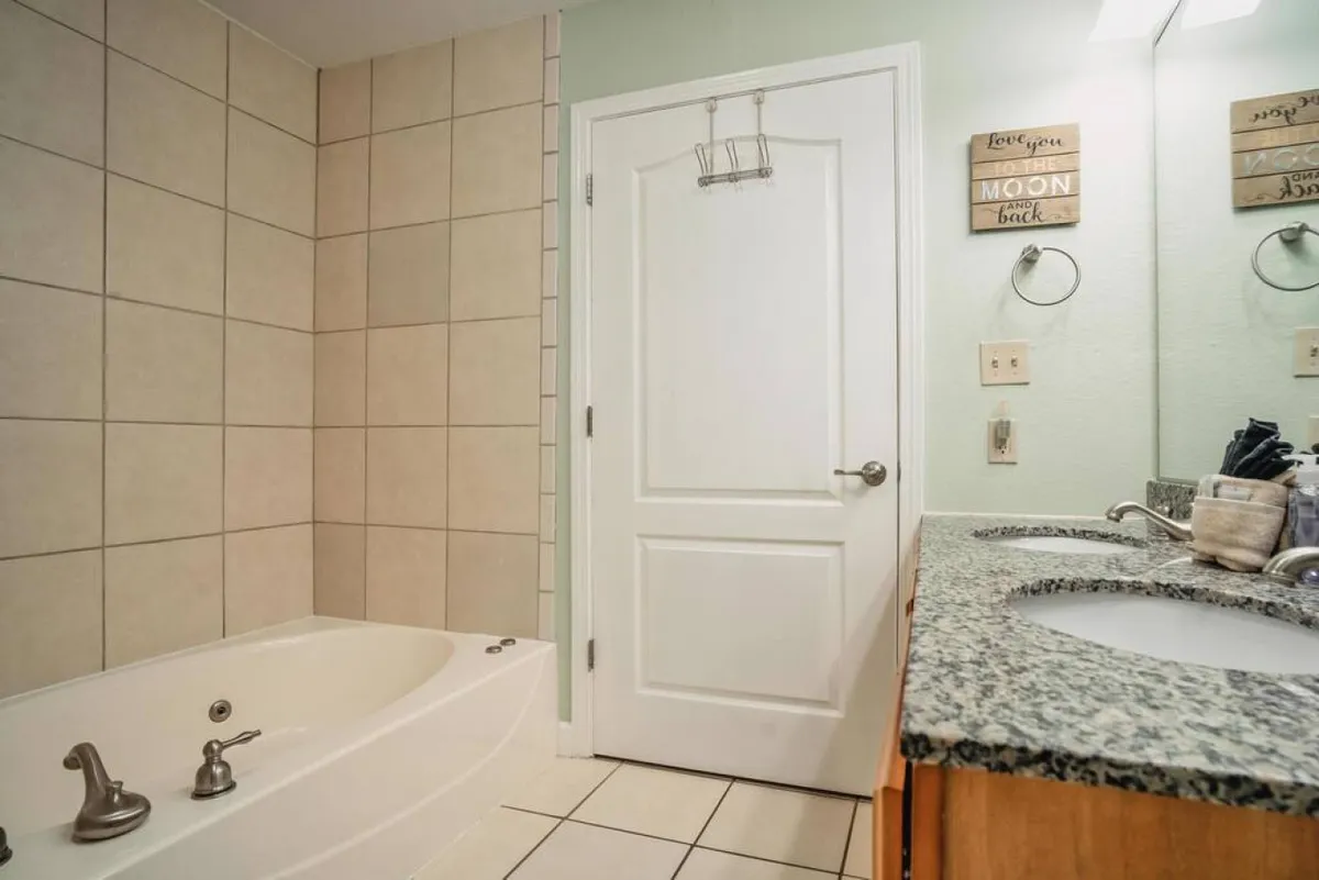 This tranquil bathroom scene centers on a spacious bathtub, vanity with sink, and decorative wall accents. The setting is serene, promoting comfort and self-care—an ideal spot for unwinding after an active day.