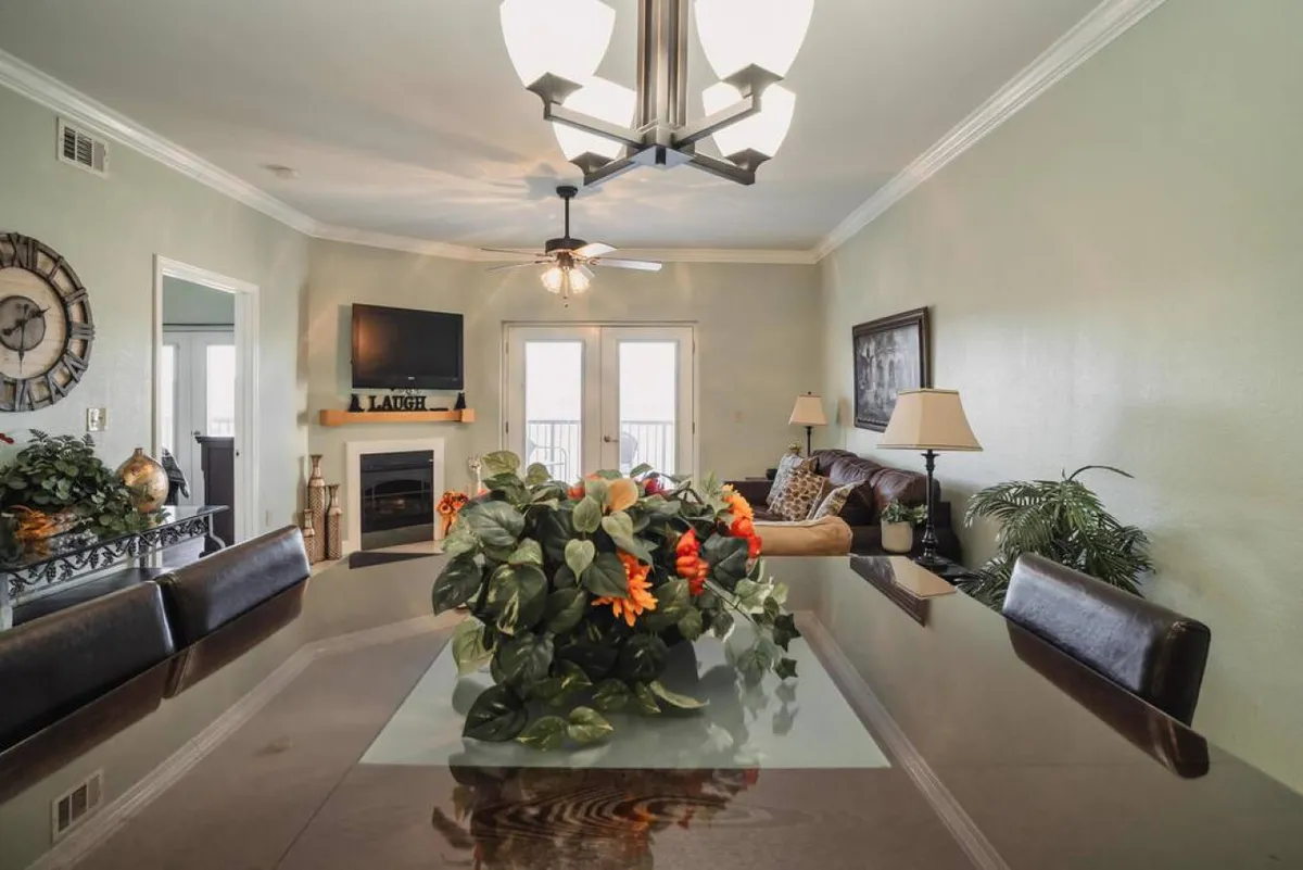 A warm, family-oriented living space featuring a dining table with a centerpiece, a fireplace, a television, and a soft sofa. The decor is cozy and inviting, encouraging both lively family dinners and cozy evenings with friends by the fire.