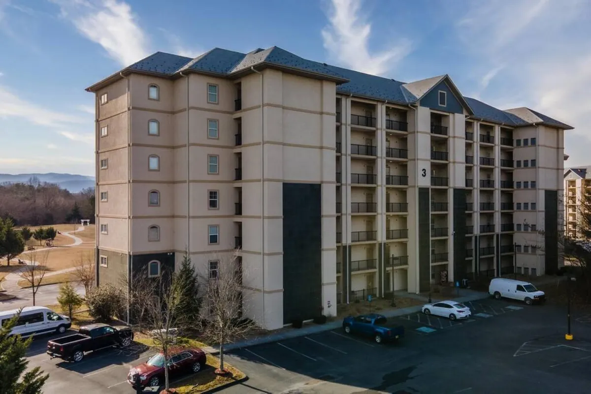 This image shows a multi-story building surrounded by lush landscape and a parking area, presenting a clear view of the property’s exterior and its integration into the wider neighborhood. The welcoming atmosphere and visible proximity to local amenities suggest easy access to the heart of Pigeon Forge.
