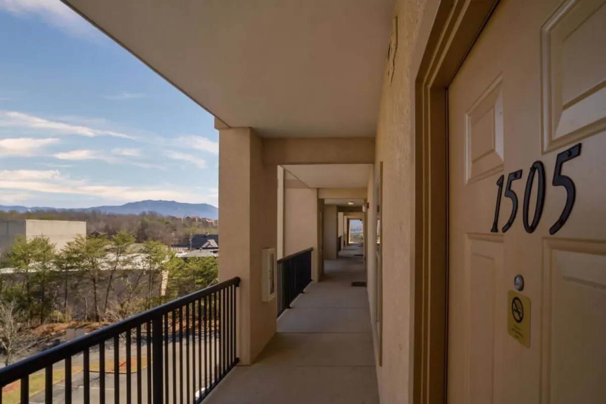 A welcoming balcony scene with a railing, a clear door marked '1505', and a breathtaking mountain backdrop. The setting is casual, offering a place for socializing, enjoying sunrise or sunset, and feeling connected to the community and natural environment.