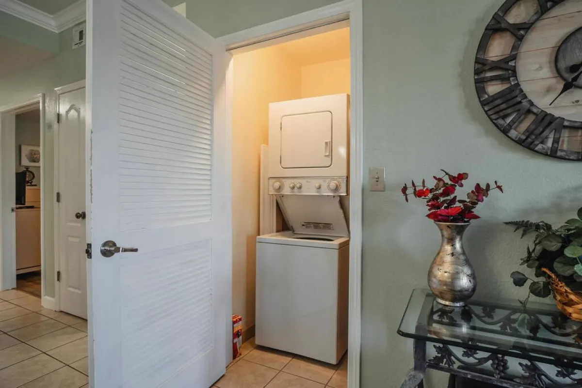 A dedicated laundry area is featured, complete with a washer and dryer, a decorative vase, and a wall clock. The space is tidy and practical, highlighting an essential amenity for day-to-day convenience.